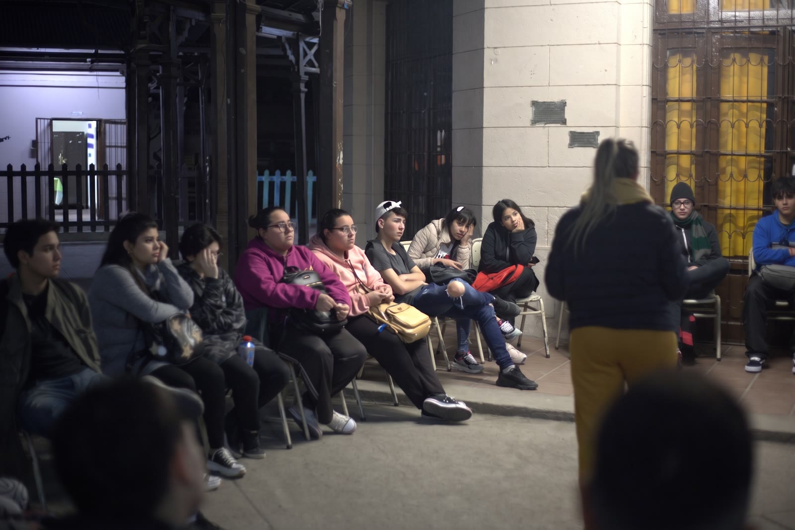Taller de prevención nocturno al aire libre con jóvenes escuchando a una coordinadora